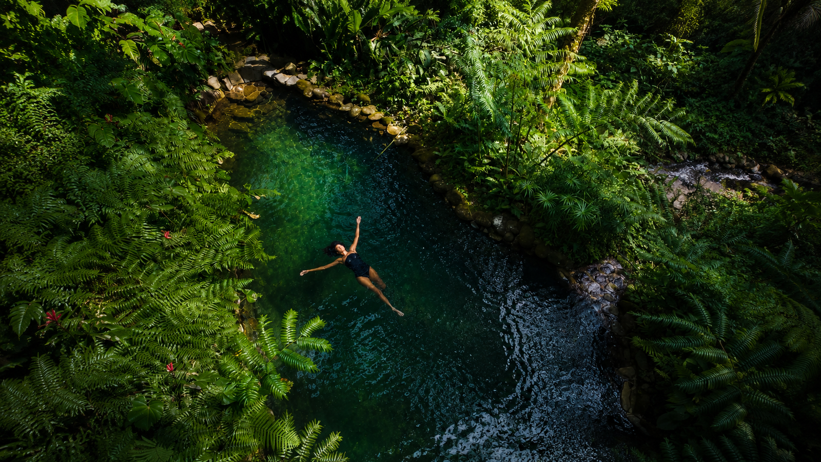 Mujer flotando en lago rodeado de naturaleza